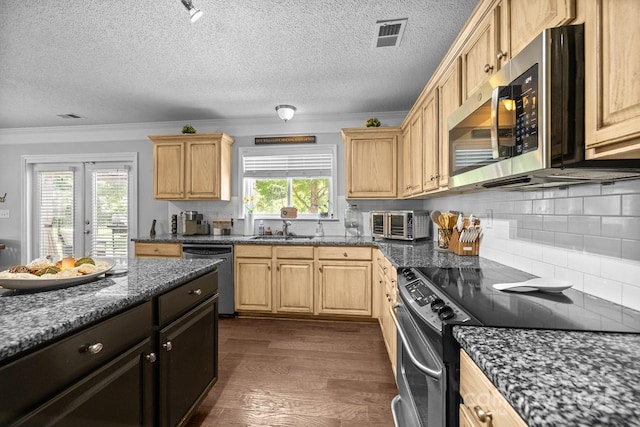 kitchen featuring appliances with stainless steel finishes, a sink, ornamental molding, plenty of natural light, and dark wood-type flooring