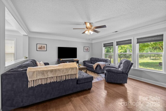 living area with crown molding, a textured ceiling, ceiling fan, wood finished floors, and baseboards