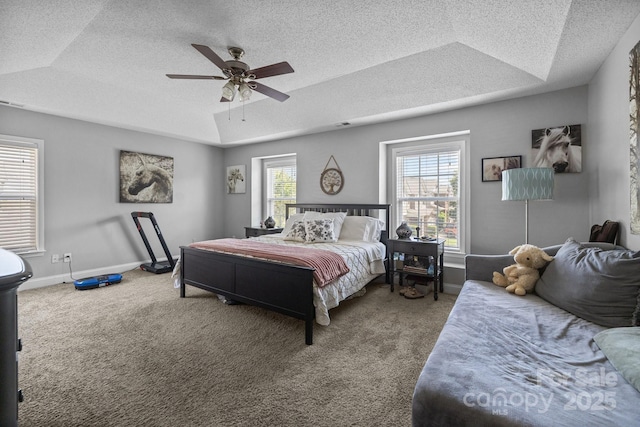 carpeted bedroom with a raised ceiling, a textured ceiling, baseboards, and a ceiling fan