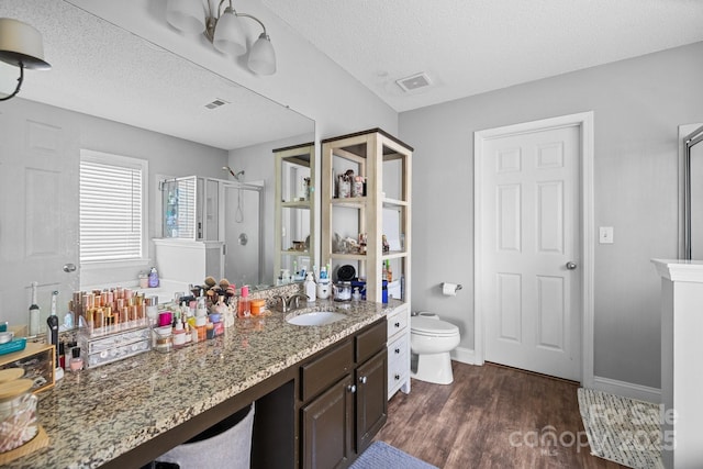 bathroom featuring wood finished floors, a shower stall, a textured ceiling, toilet, and vanity