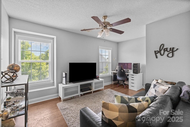 living area with ceiling fan, wood finished floors, a textured ceiling, and baseboards