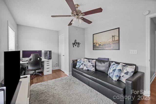 office featuring wood finished floors, a textured ceiling, ceiling fan, and baseboards