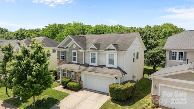 traditional-style home with concrete driveway, a garage, a front yard, and stone siding