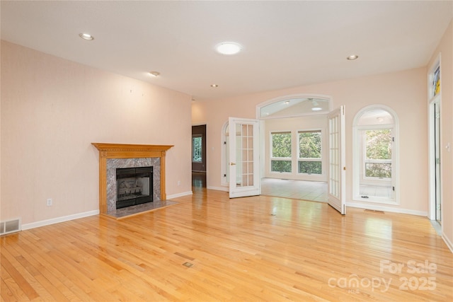 unfurnished living room featuring wood finished floors, a high end fireplace, recessed lighting, and baseboards