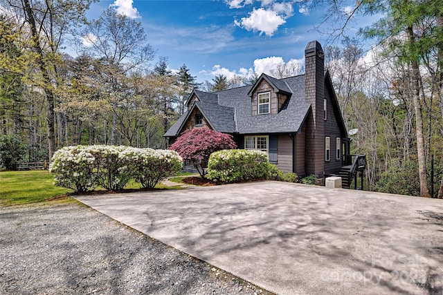 view of side of home with roof with shingles, central AC, and a chimney