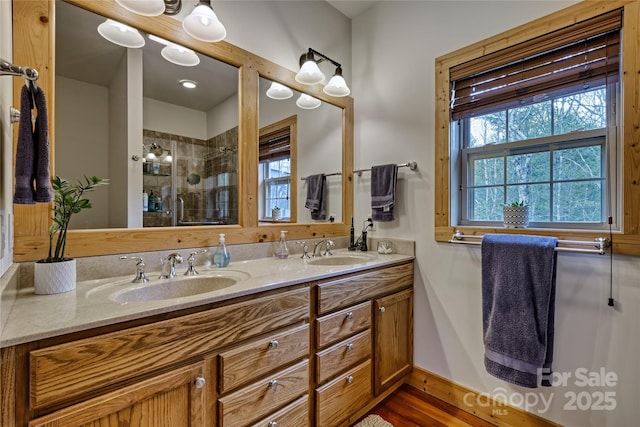 bathroom with a shower stall, double vanity, and baseboards