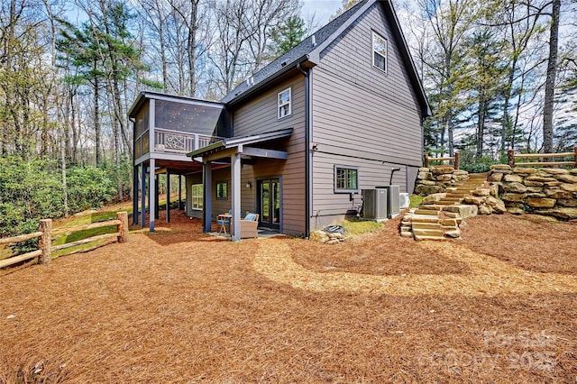 view of side of home featuring a sunroom, central AC unit, a wooden deck, fence, and stairway