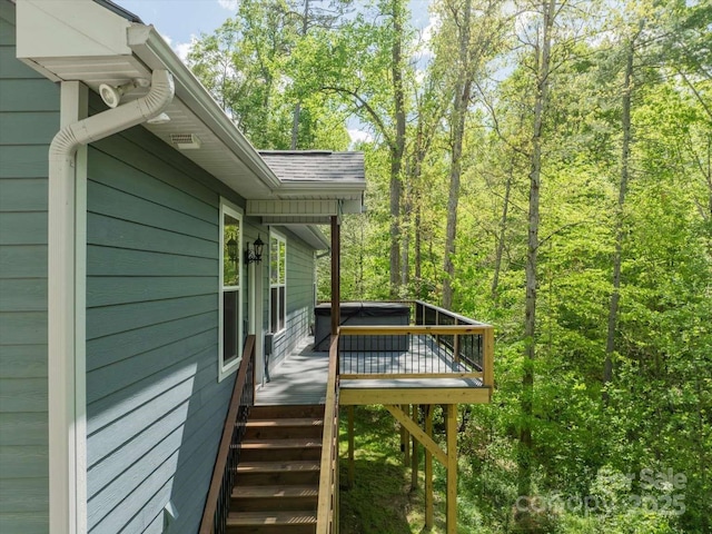 view of property exterior featuring a deck, stairway, and roof with shingles