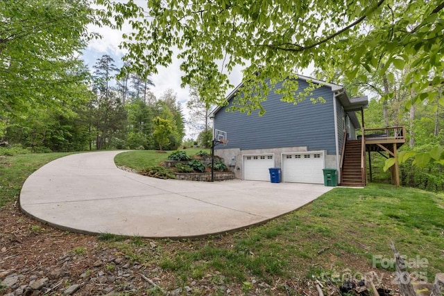 view of side of property with stairway, an attached garage, concrete driveway, a yard, and a deck