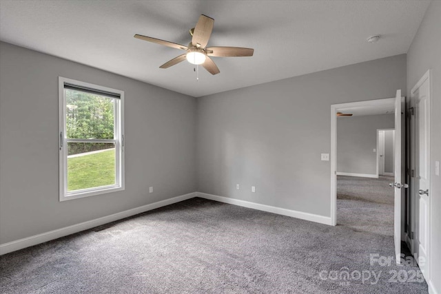 carpeted empty room with a ceiling fan and baseboards