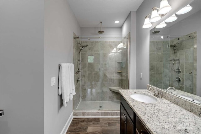 full bath featuring a shower stall, vanity, wood finished floors, and baseboards