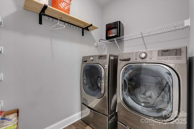 clothes washing area with separate washer and dryer, wood finished floors, and baseboards