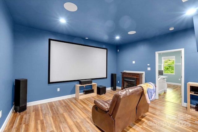 home theater room featuring light wood-style floors, recessed lighting, baseboards, and a fireplace