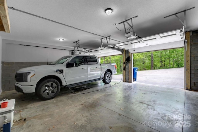 garage with concrete block wall and a garage door opener