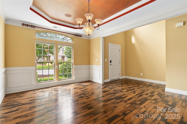 2346 Donnington Ln NW, Concord, NC 28027 - spare room with dark wood-style flooring, a tray ceiling, a chandelier, a wainscoted wall, and crown molding
