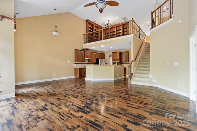 2346 Donnington Ln NW, Concord, NC 28027 - unfurnished living room with high vaulted ceiling, dark wood finished floors, ceiling fan, baseboards, and stairs