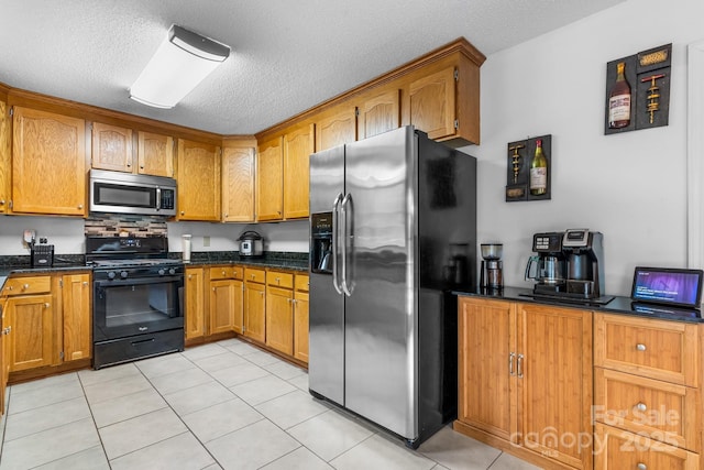 kitchen featuring appliances with stainless steel finishes, brown cabinets, a textured ceiling, and light tile patterned flooring