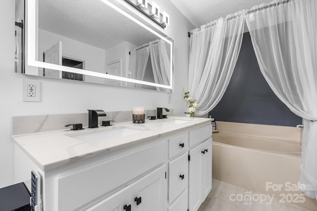 full bathroom with a textured ceiling, a garden tub, and double vanity