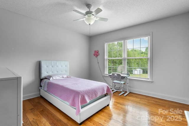 bedroom with baseboards, wood finished floors, a textured ceiling, and ceiling fan