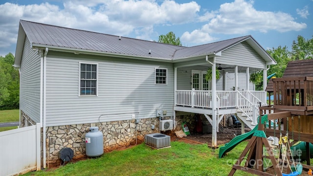 rear view of house with ac unit, cooling unit, metal roof, and a playground
