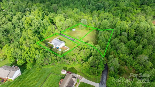 aerial view of property and surrounding area with a heavily wooded area and property parcel outlined