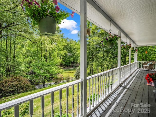 deck featuring covered porch, a yard, and view of scattered trees