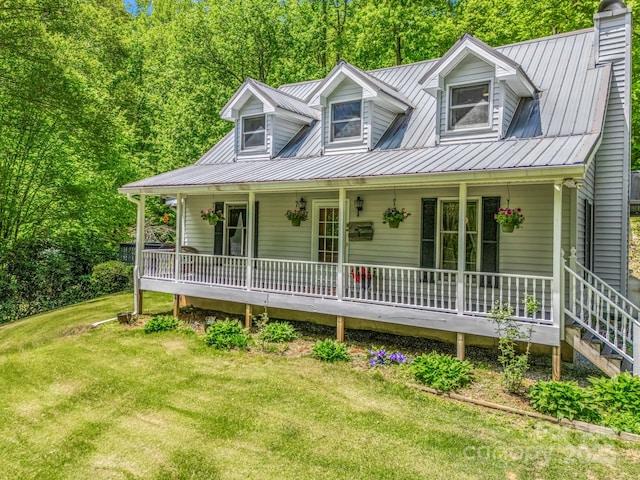 cape cod house with covered porch, a front lawn, metal roof, and a chimney