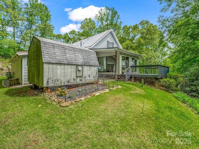 back of house with a shed, an outbuilding, a yard, and a gambrel roof