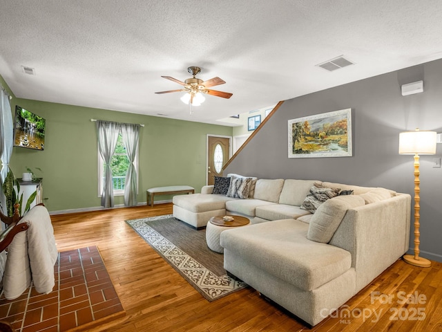 living area featuring ceiling fan, wood finished floors, a textured ceiling, and baseboards
