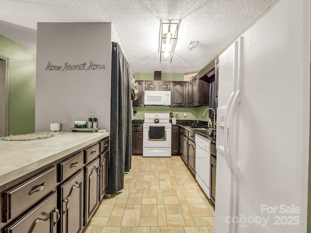 kitchen with white appliances, a sink, light stone finish flooring, a textured ceiling, and dark brown cabinetry