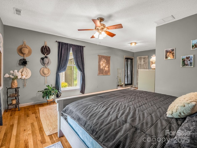bedroom with light wood-style flooring, a textured ceiling, ceiling fan, and baseboards