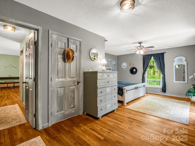bedroom with hardwood / wood-style floors, a textured ceiling, and a ceiling fan