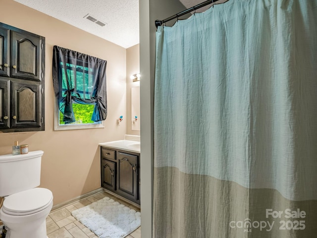 bathroom with toilet, vanity, baseboards, a textured ceiling, and tile patterned flooring