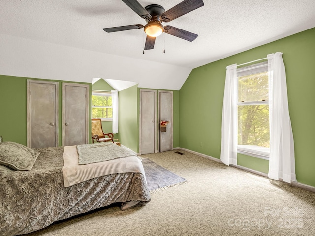 carpeted bedroom featuring lofted ceiling, baseboards, a textured ceiling, and a ceiling fan