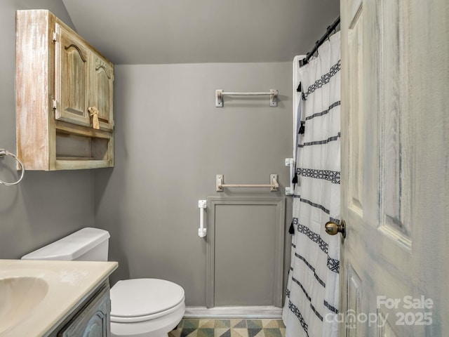 bathroom featuring toilet, vanity, a shower with shower curtain, and baseboards