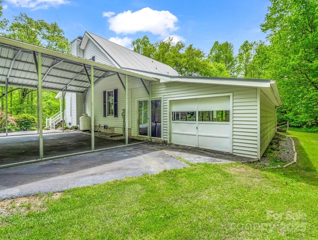 view of front of property featuring asphalt driveway, an attached garage, a front lawn, a carport, and metal roof
