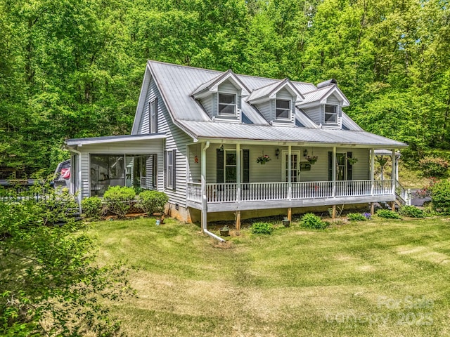 view of front of property with covered porch, a front lawn, metal roof, and a view of trees