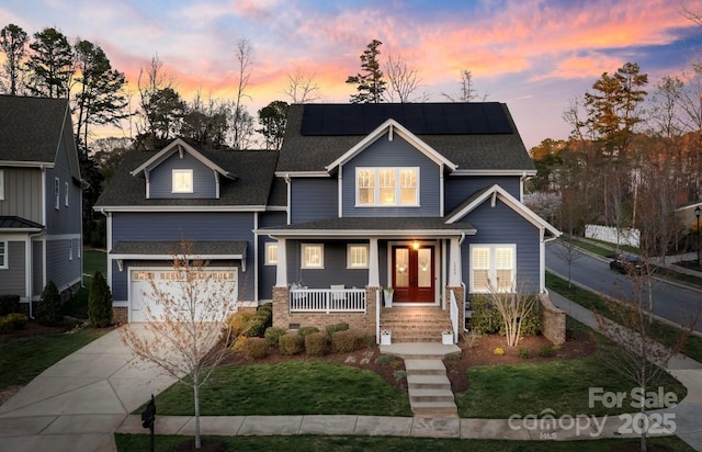 1502 Matthew Mcclure Cir, Davidson, NC 28036 - view of front facade with covered porch, concrete driveway, roof mounted solar panels, a front yard, and an attached garage