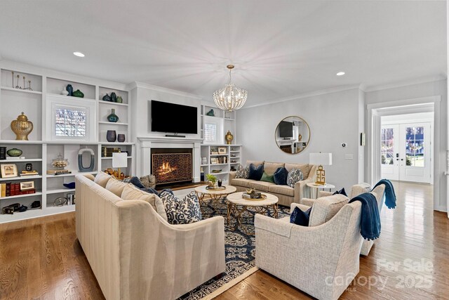 1502 Matthew Mcclure Cir, Davidson, NC 28036 - living room with a chandelier, healthy amount of natural light, wood finished floors, ornamental molding, and a warm lit fireplace