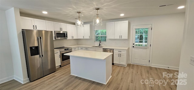 kitchen featuring appliances with stainless steel finishes, a sink, light wood-style floors, light countertops, and recessed lighting