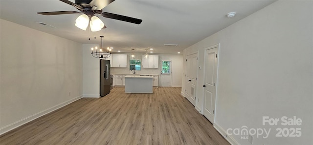 kitchen featuring high end refrigerator, light wood-type flooring, a center island, a ceiling fan, and light countertops