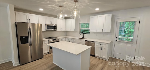 kitchen with stainless steel appliances, a sink, light wood-style flooring, white cabinetry, and recessed lighting