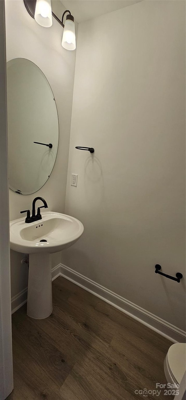 bathroom featuring wood finished floors, baseboards, a sink, and toilet