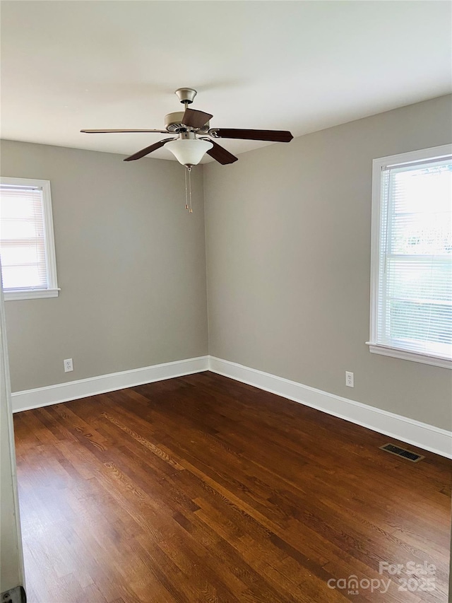 spare room with dark wood-style flooring, a ceiling fan, and baseboards