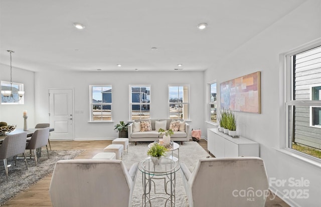 living area with a chandelier, plenty of natural light, light wood-style flooring, recessed lighting, and baseboards