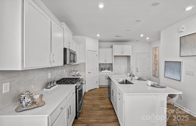 kitchen featuring a sink, appliances with stainless steel finishes, white cabinetry, light countertops, and decorative backsplash