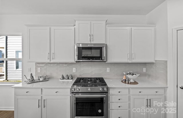 kitchen with stainless steel appliances, white cabinets, and tasteful backsplash