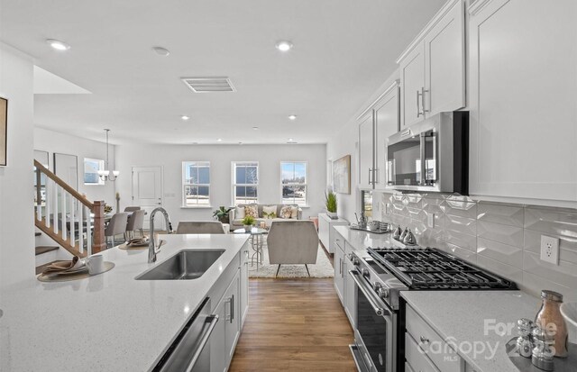 kitchen featuring stainless steel appliances, a sink, wood finished floors, decorative backsplash, and recessed lighting