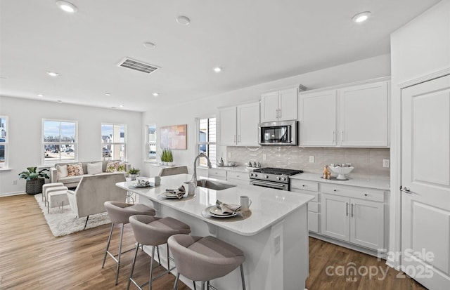 kitchen featuring stainless steel appliances, a sink, backsplash, healthy amount of natural light, and recessed lighting