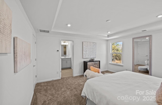 carpeted bedroom featuring a tray ceiling, baseboards, recessed lighting, and ensuite bathroom